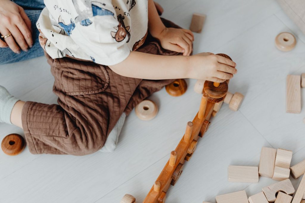 A child playing with wooden blocks and toys on the floor, engaging in creative play.